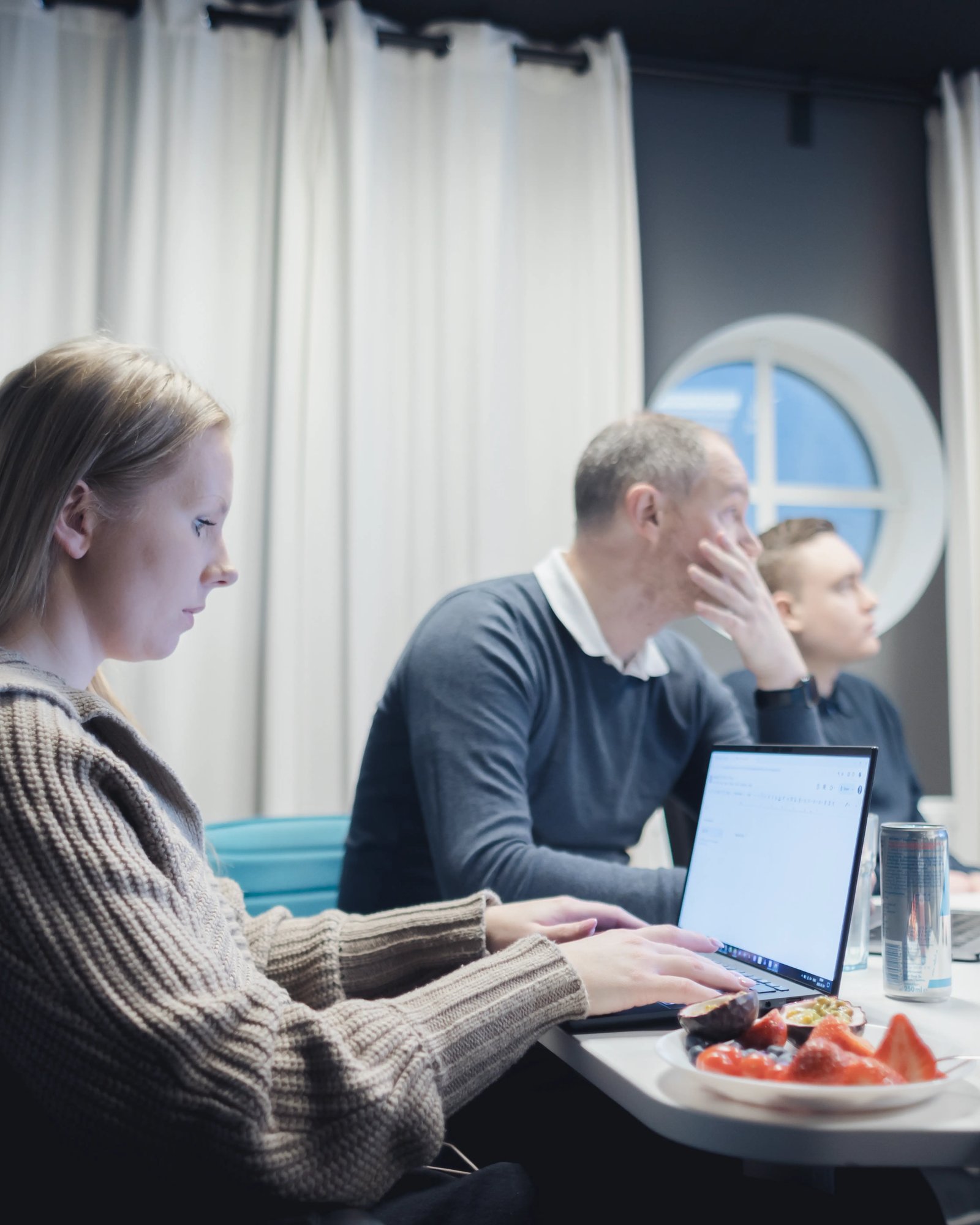 A picture of Madeleine sitting in front of her laptop in one of TeQflo's meeting rooms