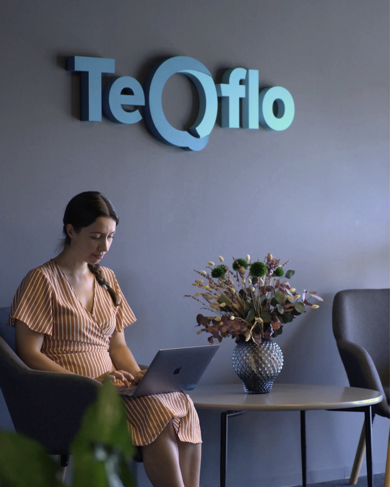 A picture of Maia sitting in the entrance to the TeQflo office with her lamptop on her lap
